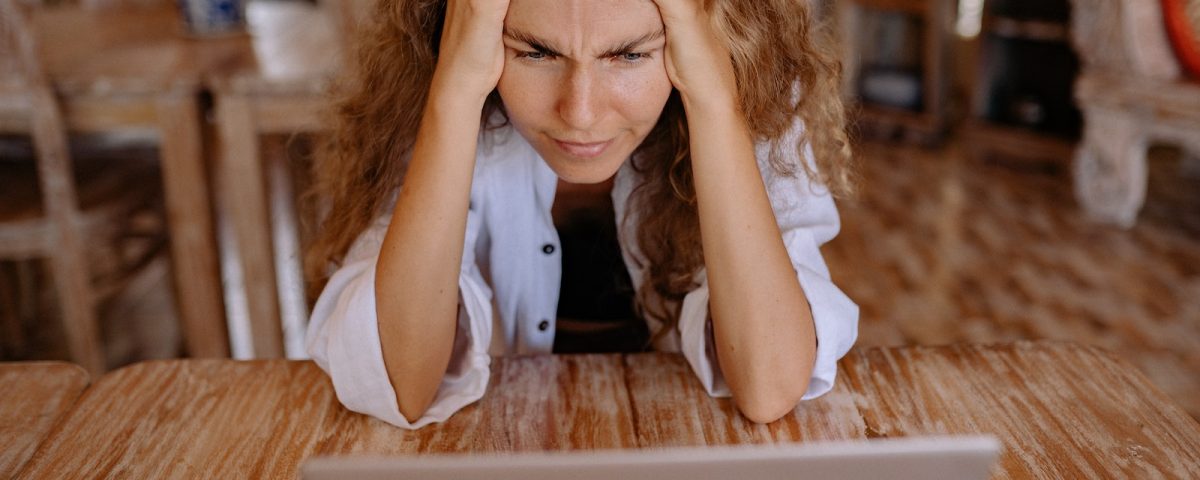 Photo of Woman Leaning on Wooden Table While Looking Upset